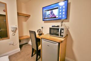 um quarto com uma secretária, um micro-ondas e uma televisão em Central Studios Gloucester Place by Roomsbooked em Cheltenham