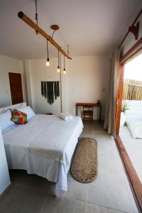 um quarto com uma cama branca e uma mesa em Pousada Movimento em Praia do Preá
