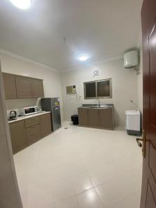 a large kitchen with brown cabinets and a white tile floor at قاردن وحدات سكنية خاصة in Al Madinah