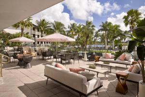 d'une terrasse avec des tables, des chaises et des palmiers. dans l'établissement The Cottages at PGA National Resort, à Palm Beach Gardens