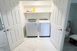 two washing machines in a small kitchen with a door at Stylish and luxurious apartment basement unit in Longueuil