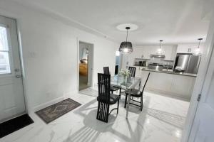 a white kitchen with a glass table and chairs at Stylish and luxurious apartment basement unit in Longueuil