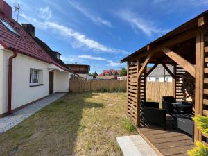 a garden with a wooden pavilion next to a house at Chatka Rybaka - wygodny dom z podwórkiem in Łeba