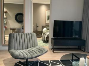 a living room with a chair and a flat screen tv at 5 Star Elegant Apartments, Ellipse Waterfall City, Midrand, Johannesburg in Midrand