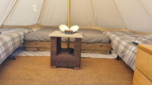 a room with two beds and a table in a tent at Route 47 Glamping Bell Tents in Cross Hands