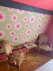 three chairs and a table in a room with flowers on the wall at An Artist Created it in Middelburg