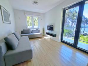 a living room with a couch and a tv at SEA & YOU Apartament z widokiem na morze - Dwie Sosny in Ustronie Morskie
