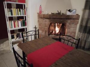 een woonkamer met een open haard en een houten tafel met een rode deken bij Etna Hiking House in Nicolosi
