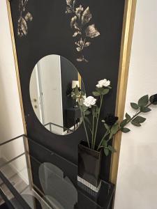 a bathroom with a mirror and a vase with flowers at Aurora Flowers - Two rooms and free parking near train station in Modena