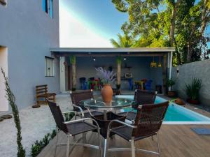 a patio with a glass table and chairs next to a pool at Recanto Manoah MAR in Caraíva