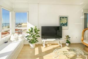 a living room with a large television and a white couch at Ático Almería. Paseo marítimo Roquetas de Mar in Roquetas de Mar