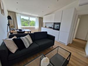 a living room with a black couch and a kitchen at Apartmani Maritimo in Seline