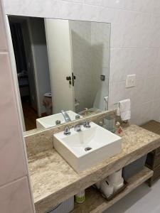 La salle de bains est pourvue d'un lavabo blanc et d'un miroir. dans l'établissement Quartinho Copacabana-Posto 5, à Rio de Janeiro