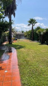 einen Garten mit Palmen und einem Ziegelweg in der Unterkunft Villa Claudia Relais in Mirto