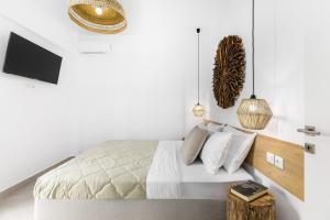 a white bedroom with a bed with a wooden headboard at Pel Mar in Pefkochori