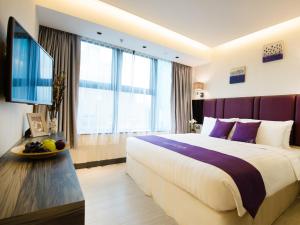 een hotelkamer met een groot bed en een televisie bij The Bauhinia Hotel - Tsim Sha Tsui in Hong Kong