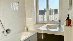 a white bathroom with a sink and a window at Homely Stay Apartment 2 in Sankt Pölten