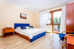 um quarto com uma cama azul e uma grande janela em Willa Krystyna em Władysławowo