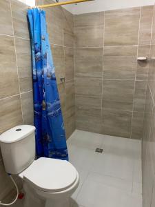 a bathroom with a toilet and a blue shower curtain at Cabaña Villa Mary-Aguachica in Aguachica