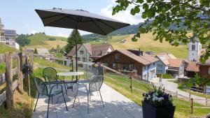 une terrasse avec une table, des chaises et un parasol dans l'établissement Haus an sonniger Lage, schöner Blick auf Alpstein, à Urnäsch
