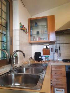 una cocina con fregadero de acero inoxidable y armarios en Andrea's House en Fiumicino