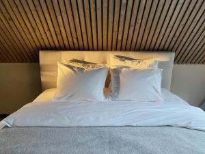 a bed with white pillows and a wooden headboard at Heinaläku puhkemaja loft in Paope