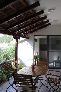 een patio met een houten tafel en stoelen bij Apartments Leo Katić in Lastovo