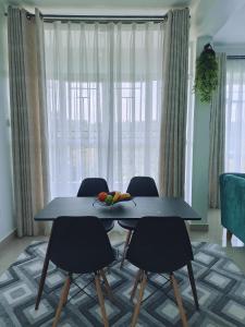 a table and chairs in a living room with a window at Sky Nest Grey point 306 in Kericho