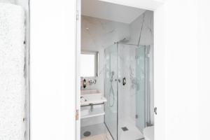 a white bathroom with a shower and a sink at Avenida Viana Boutique Suites in Viana do Castelo