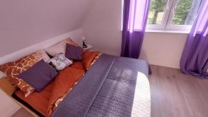 1 cama en un dormitorio con cortinas moradas en Zielony Zakątek Demlin, en Demlin