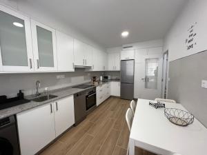 una cocina con armarios blancos y una mesa con sillas. en Cedemar 2, en Cedeira
