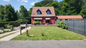 ein rotes Haus mit einem Hof mit einem Zaun in der Unterkunft La Gitane in Saint-Valery-sur-Somme