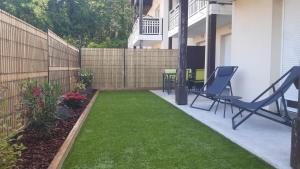 a backyard with chairs and a fence and grass at RESIDENCE LE DOMAINE DE MARTHIAS in Le Teich