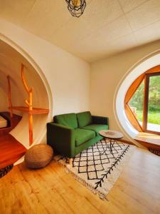 a living room with a green couch and a window at Casa Florestal - Fatela - Hobbit House , Cabins in Fatela