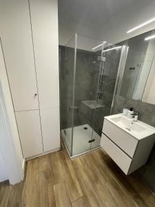 a white bathroom with a shower and a sink at Apartament Dziwnów in Dziwnów