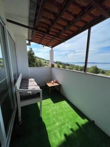 a balcony with a bed and a table with green grass at Studio apartment in Ivan Dolac +12 photos