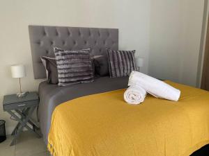 a bedroom with a large bed with a yellow blanket and pillows at Ballito Hills Lifestyle 1 Bed in Ballito