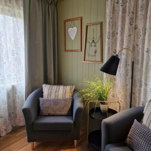 a living room with a couch and a chair and a lamp at Birk Husky - guesthouse & cabins in Svanvik