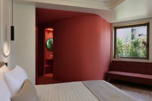 una camera da letto con una parete con accento rosso e una finestra di DWELL - Elegant City Stay ad Atene
