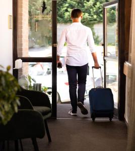 a woman walking out of a door with a suitcase at Penzion & Wellness Zoborska in Nitra