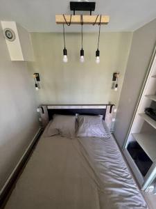 uma pequena cama num pequeno quarto com luzes em Studio à 50m à pieds de la plage em Neufchâtel-Hardelot