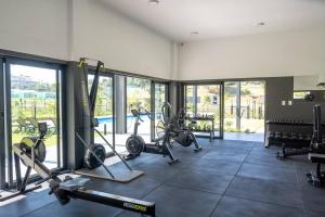 a gym with treadmills and machines in a room with windows at Gorgeous Ballito One Bedroom apartment in Ballito