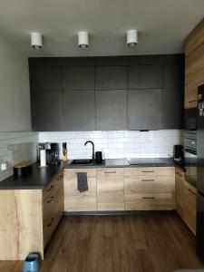 a kitchen with wooden cabinets and a black counter top at Apartament w Parku nad Kanałem in Bydgoszcz