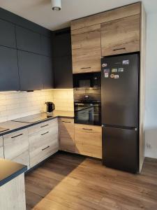 a kitchen with a black refrigerator and wooden cabinets at Apartament w Parku nad Kanałem in Bydgoszcz