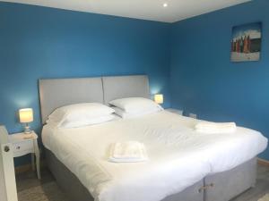 a blue bedroom with a large bed with white pillows at Kingfisher Glamping Cabin in Bodmin