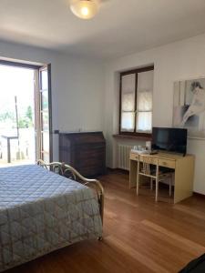 een slaapkamer met een bed en een bureau met een televisie bij Casa ivana in Borghetto di Vara