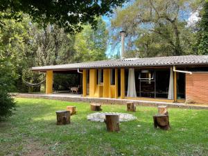 uma casa amarela com troncos à frente. em Casa de vidro em Campos do Jordão