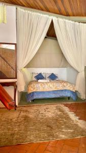 um quarto com uma cama com cortinas e um tapete em Casa de vidro em Campos do Jordão