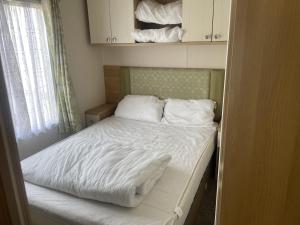a small bed with white sheets and pillows in a room at Stunning 3-Bed Caravan in Clacton-on-Sea in Clacton-on-Sea