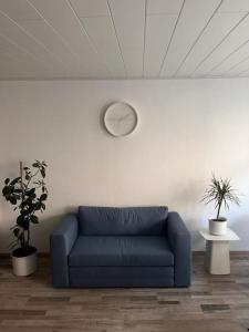 a blue couch in a room with a clock on the wall at Weserbutze in Bodenwerder